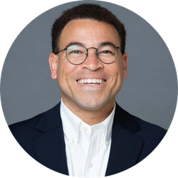 Alec Harold wearing a suit and smiling