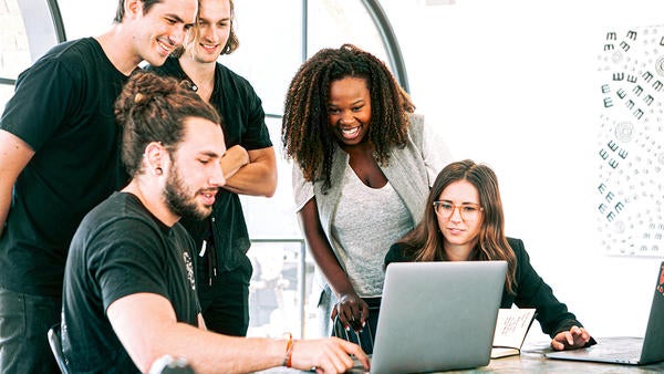 group of students looking at a laptop