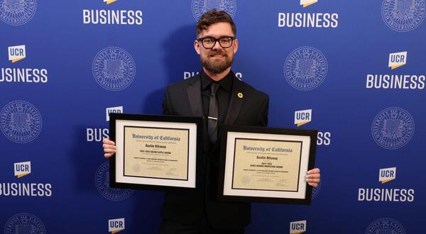 Austin Attaway holding his two award certificates: one for the Golden Apple Award, and another for the James Merino Innovation Award