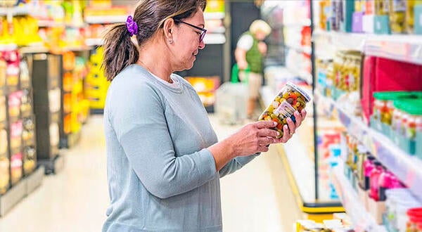 A woman diserns prices at a grocery store (Getty Images)