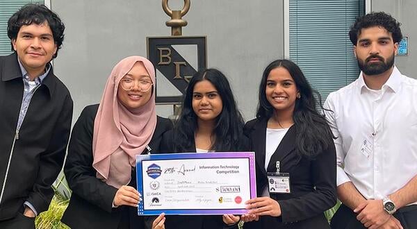 Competition team in front of cpp business building with check