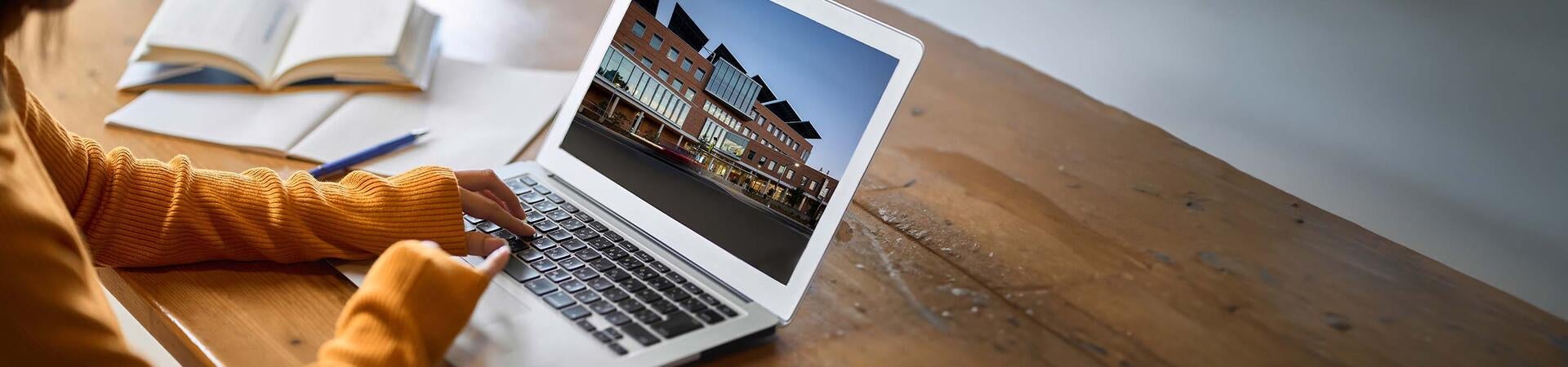 A student viewing the UCR School of Business through her laptop screen.
