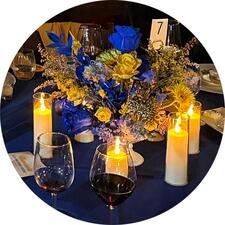 Illuminate dinner table with flower decoration and candles blue and gold