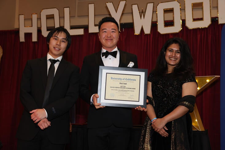 Rich Yueh standing proud as he holds his certificate for the Shulman Endowed Excellence in Teaching Award