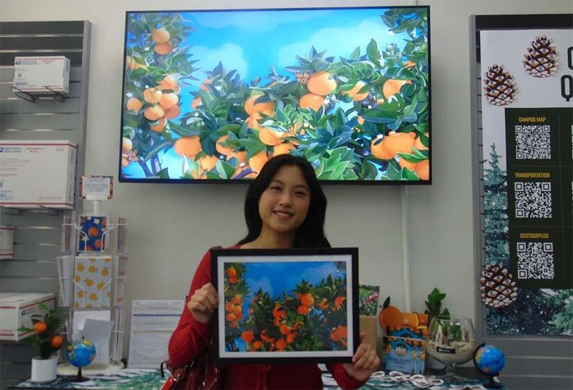 Valerie Cheng with a framed picture of her winning R'Card contest design